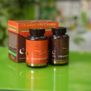 na zelenom stolu se nalaze dve bočice GrandCaps čage sa dihidrovercetinom koje simbolišu dnevnu i noćnu formulu. Iza njh nalazi se kutija u kojoj ruski preparat dolazi.